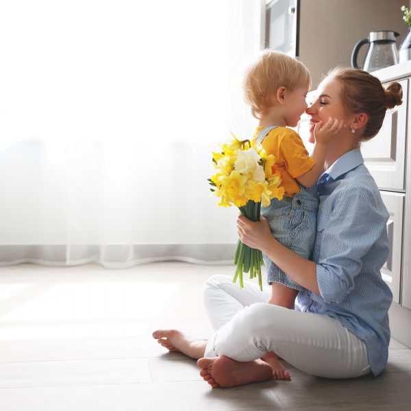 happy mother's day! baby son congratulates mother on holiday and gives flowers